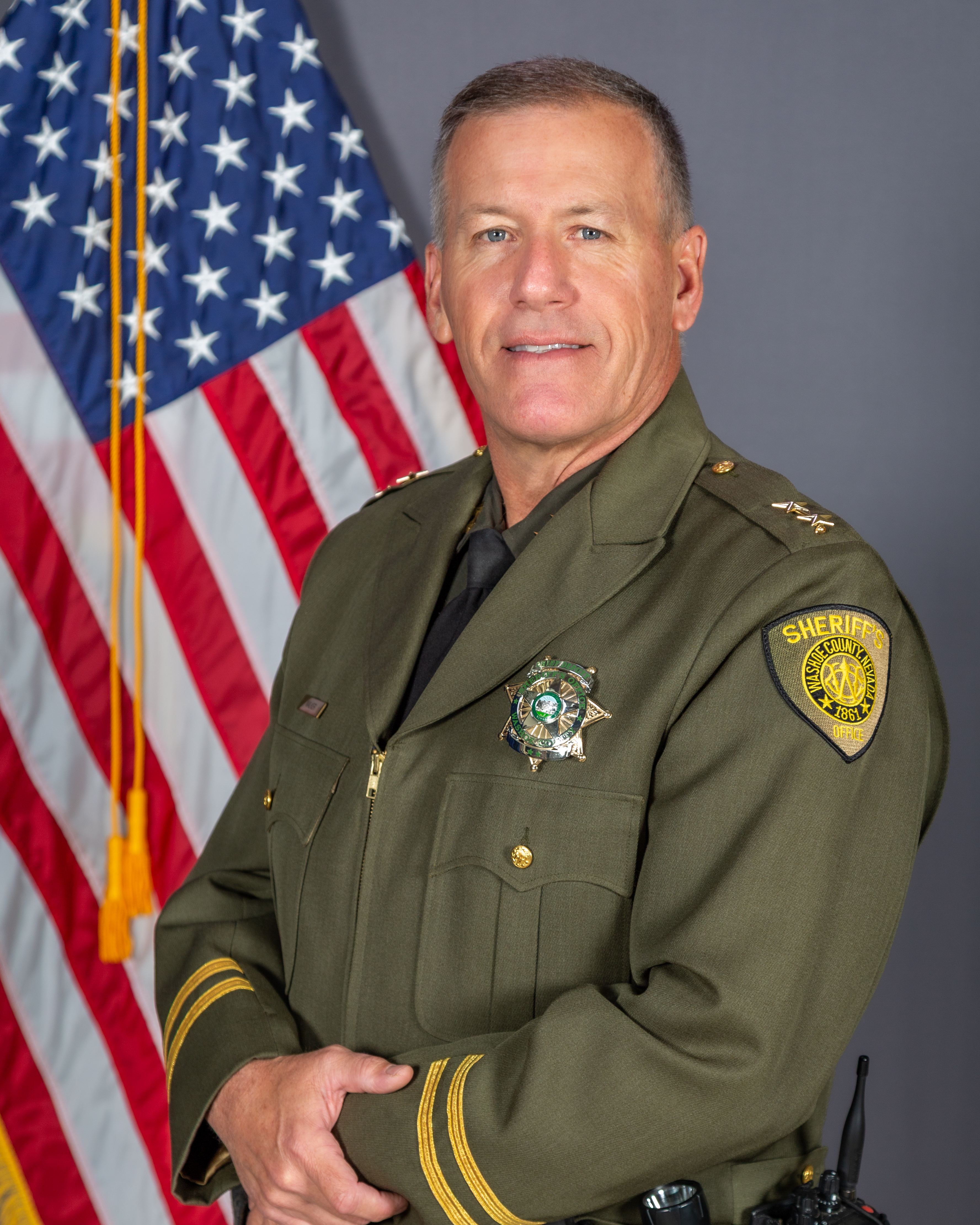 Assistant Sheriff Jason Walker, in WCSO uniform, poses in front of the American Flag